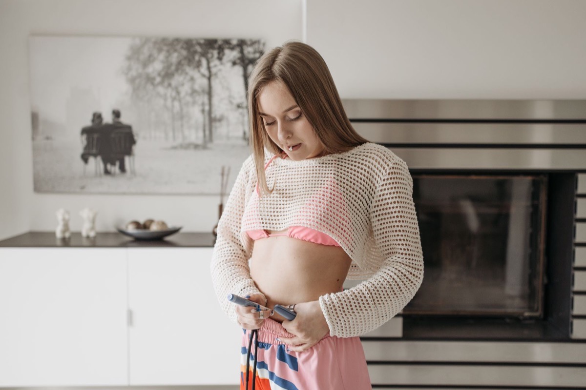 A person administering a subcutaneous injection pen to the abdomen at home — representing the GLP-1 plus AOD-9604 / Fragment 176-191 stack conversation