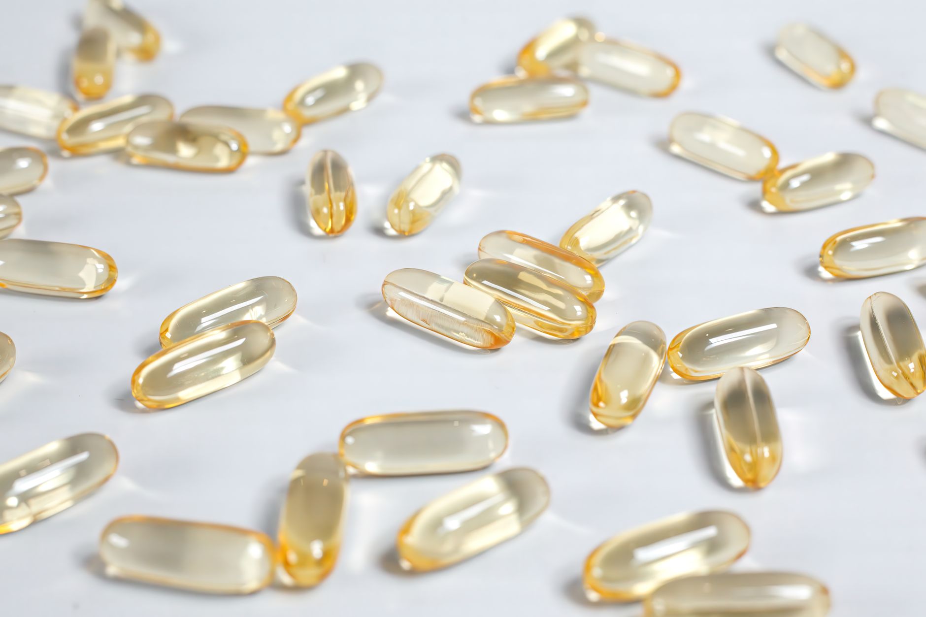 Amber softgel oral testosterone capsules scattered on a clean clinical white surface, illustrating oral TRT medication