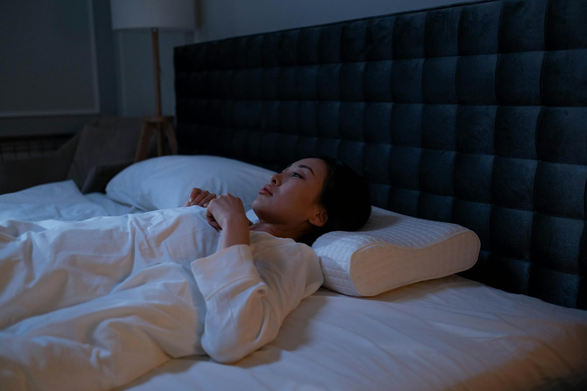 Person sleeping in dark bedroom — sleep debt metabolic damage